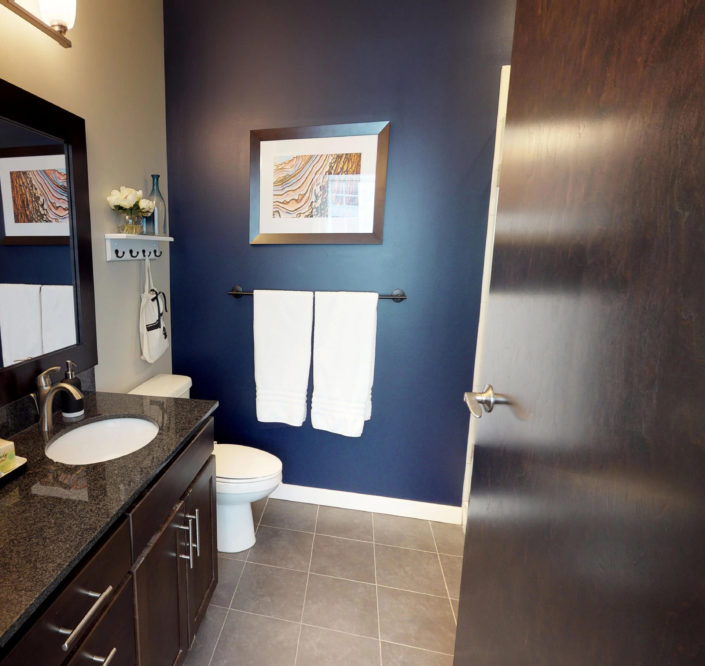 Guest suite bathroom with brown cabinets and granite countertops